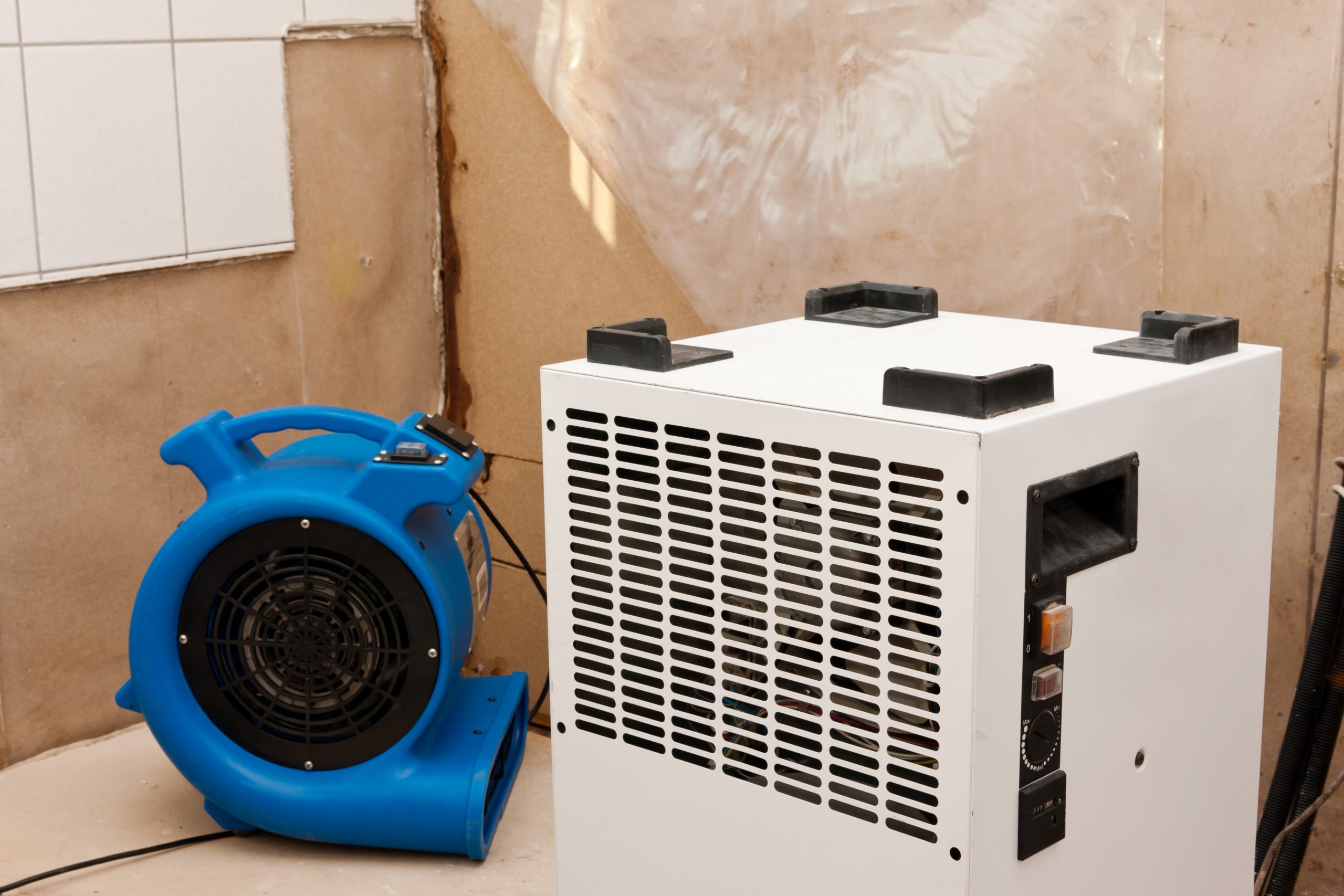 Air mover and dehumidifier drying a room after water damage